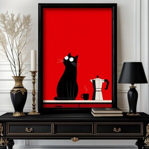 Puede incluir: Una lámina de arte mural enmarcada rectangular con un fondo rojo sólido que muestra un gato negro sentado sobre una encimera junto a una pequeña taza de café negra y una cafetera italiana plateada. El gato tiene grandes ojos blancos mirando arriba.