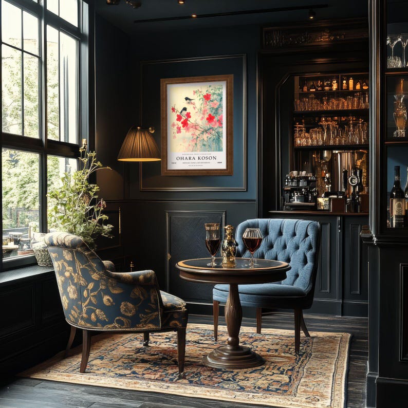 May include: A dark blue armchair with tufted upholstery sits in a room with dark wood furniture and a framed print of a bird and flowers. The print is titled "Ohara Koson".