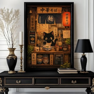 Könnte beinhalten: Ein gerahmter Kunstdruck, der eine schwarze Katze mit Schürze in einem Ramen-Laden zeigt. Die Szene enthält japanischen Text, eine rote Laterne, Holzregale mit Schüsseln und eine dampfende Schüssel Nudeln auf einem schwarzen Konsolentisch.