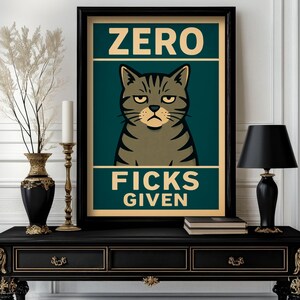 May include: A framed poster with a grumpy cat illustration. The poster reads "ZERO FICKS GIVEN" in bold text. The cat is gray with black stripes and a stern expression. The poster is displayed on a black table with gold accents.