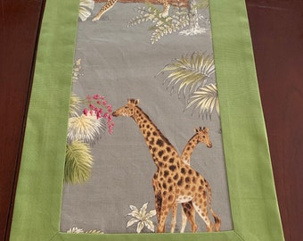May include: A green table runner with a gray background featuring a leopard and giraffes in a jungle setting.