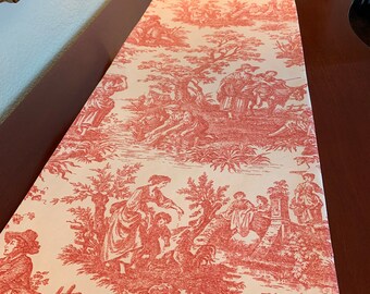 Può includere: Un runner da tavolo in toile rosso e bianco con un design country francese che presenta una scena pastorale con persone e alberi.