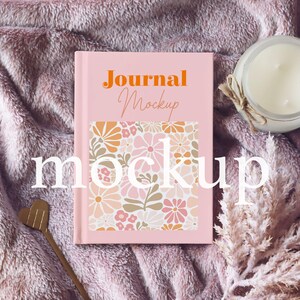 May include: Pink journal mockup with a floral pattern on the cover. The text "Journal Mockup" is printed in orange on the cover.