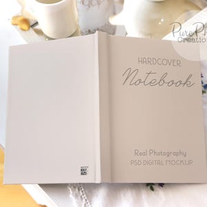 May include: A hardcover notebook mockup with the text "HARDCOVER Notebook" and "Real Photography PSD DIGITAL MOCKUP" on a white surface.