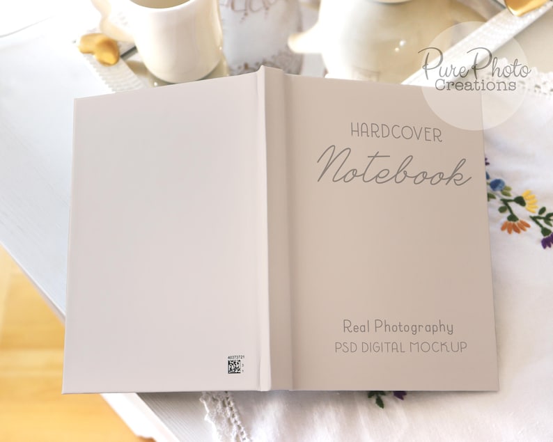 May include: A hardcover notebook mockup with the text "HARDCOVER Notebook" and "Real Photography PSD DIGITAL MOCKUP" on a white surface.