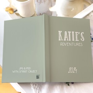 May include: A green journal with the text "KATIE'S ADVENTURES 2024" on the front cover. The back cover has the text "JPG & PSD WITH SMART OBJECT".
