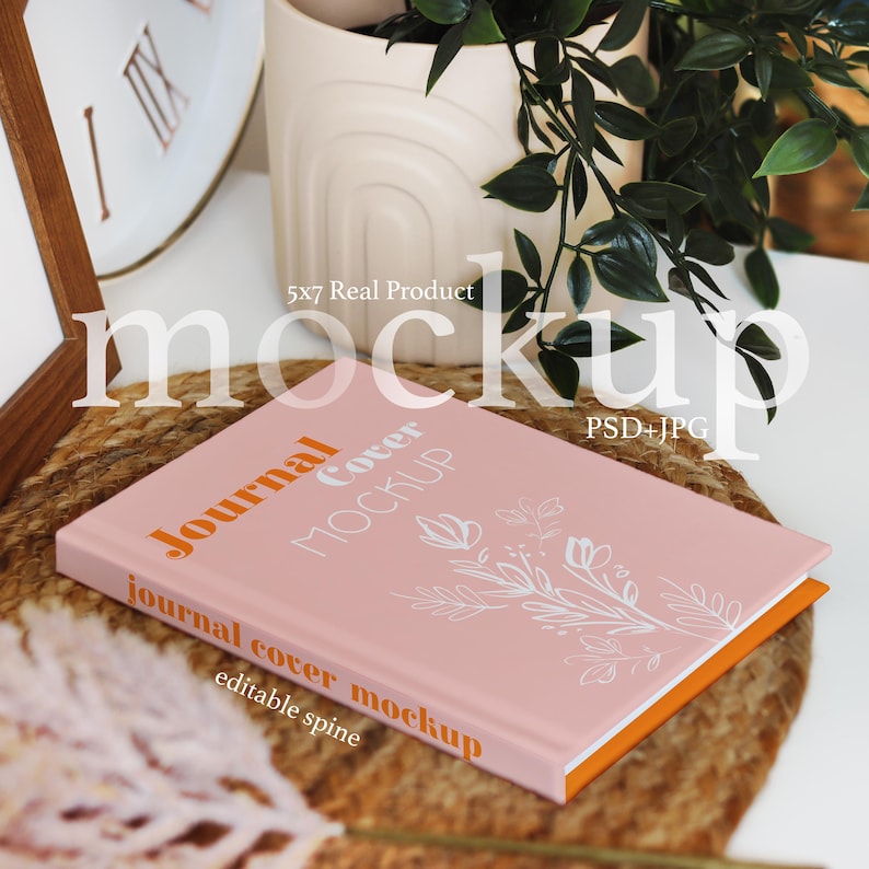 Pode incluir: Uma maquete de capa de di&aacute;rio rosa com um design floral e o texto "Journal Cover Mockup" e "journal cover mockup" com uma lombada edit&aacute;vel.