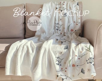 May include: White throw blanket with a floral pattern in shades of pink, blue, and green. The blanket is draped over a light brown couch. The text "Blanket Mockup" and "Pure Photo Creations" is visible in the image.