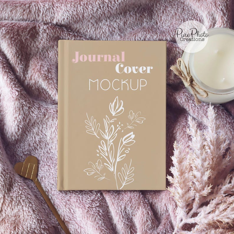 May include: A tan journal cover mockup with the text "Journal Cover Mockup" in white. The cover features a white floral design.