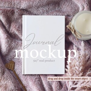 May include: White journal mockup with the text "Journal mockup 5x7" real product" on a pink fuzzy blanket with a candle and dried flowers.