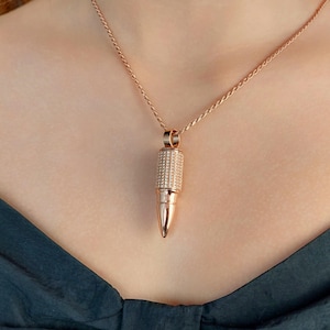 Peut inclure: Un collier en or rose avec un pendentif en forme de balle recouvert de pierres de zircone cubique transparentes.