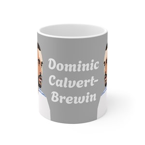 Könnte beinhalten: Weißer Keramikbecher mit grauem Hintergrund. Er zeigt ein stilisiertes Porträt und den Text "Dominic Calvert-Brewin" in Weiß. Der Becher hat einen weißen Griff und ein weißes Inneres.