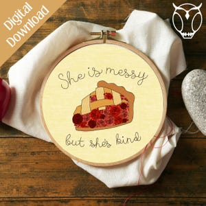 May include: A yellow embroidery hoop with the text "She is messy but she's kind" and a cartoon image of a slice of cherry pie with a lattice crust.