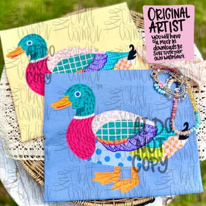 Può includere: Due magliette con un design di anatra colorata. Una maglietta è giallo chiaro, l'altra azzurra. L'anatra ha la testa turchese, il petto rosa e le ali patchwork. Il testo "ORIGINAL ARTIST" è su un quadrato rosa.