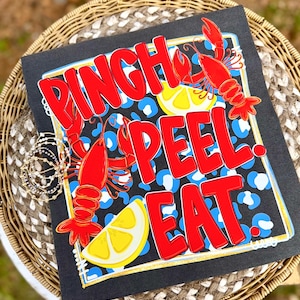 May include: Black square with the words "PINCH, PEEL, EAT" in red, with red crawfish and lemon slices. The background has a blue and white leopard print design. The border is gold.