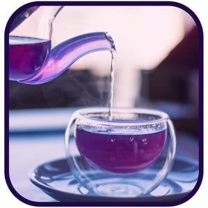 May include: A glass teapot pouring purple tea into a double-walled glass cup. The tea is steaming.