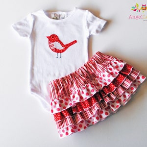 May include: A white bodysuit with a red bird applique and a red and white polka dot skirt with ruffles.