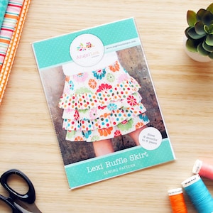 May include: A sewing pattern for a Lexi Ruffle Skirt for children aged 6 months to 7 years. The pattern cover features a colourful floral print skirt with multiple ruffles. The pattern is from Angellies Designs.