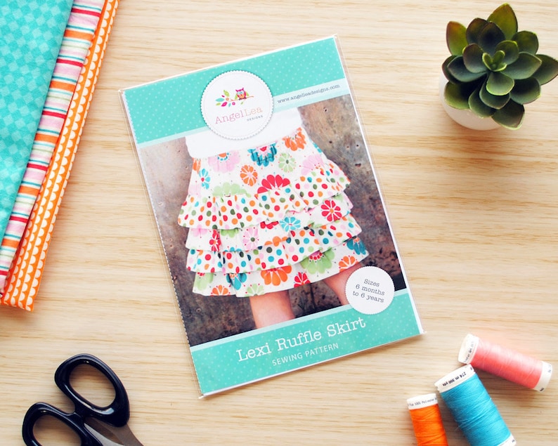May include: A sewing pattern for a Lexi Ruffle Skirt for children aged 6 months to 7 years. The pattern cover features a colourful floral print skirt with multiple ruffles. The pattern is from Angellies Designs.