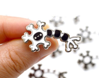 May include: Silver-toned enamel pin featuring a cartoon neuron with a smiling face. The neuron has a star-shaped cell body and a long axon with black segments.