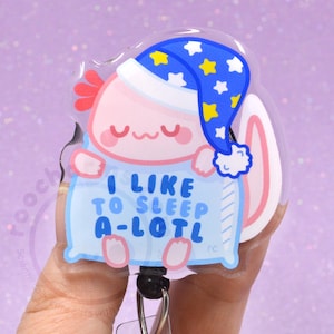 May include: A clear, acrylic axolotl badge reel featuring a sleeping axolotl wearing a blue nightcap with yellow stars. The axolotl is holding a blue pillow with the text "I LIKE TO SLEEP A-LOTL".