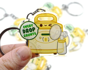 May include: A yellow and white acrylic keychain with a cartoon illustration of a breast pump. The keychain has a green circle with the text "Every Drop Counts".