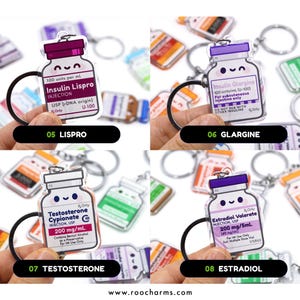 May include: Keychains featuring cartoon-style medicine bottles with labels for Lispro, Glargine, Testosterone, and Estradiol. Each keychain has a black ring and a smiling face design. The text on the bottles includes medication names and dosages.