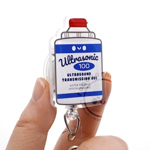 May include: A badge reel featuring a white, blue, and red acrylic charm shaped like a bottle of Ultrasonic 100 Ultrasound Transmission Gel. The label includes the text Ultrasonic 100, Ultrasound Transmission Gel, Water Soluble, and Hypoallergenic.