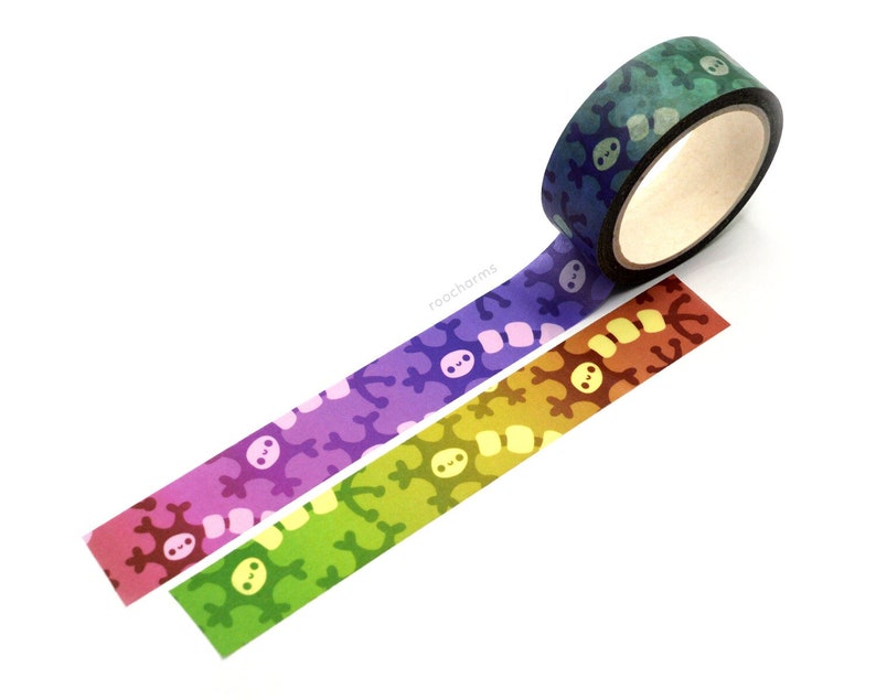 K&ouml;nnte beinhalten: Drei Rollen Washi-Tape mit einem sich wiederholenden Muster aus einem l&auml;chelnden Gesicht und einem Knochen. Das Band ist in Gr&uuml;n-, Orange- und Lilat&ouml;nen.