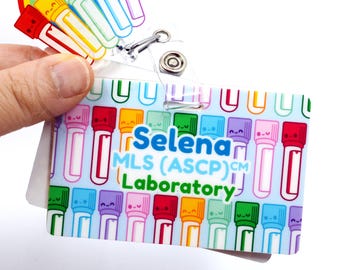 May include: A blue and white ID badge with a colorful pattern of cartoon test tubes. The text "Selena MLS (ASCP)CM Laboratory" is printed on the badge.