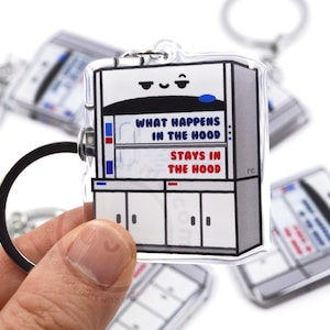 May include: A white and gray plastic keychain shaped like a laboratory fume hood with the text "What happens in the hood stays in the hood".