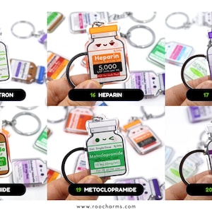May include: Keychains featuring various medication vials, including Ondansetron, Heparin, Botulinum, Furosemide, Metoclopramide, and Caffeine Citrate. Each keychain has a unique color scheme and label with drug information. The keychains are held up by a hand.