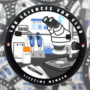 May include: A black and white sticker with the text "Lab Sciences Fan Club Lifetime Member" around the edge. The sticker features a cartoon illustration of a microscope, beakers, and other lab equipment.