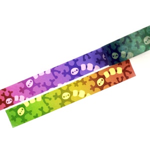 K&ouml;nnte beinhalten: Drei Rollen Washi-Tape mit einem Farbverlaufsmuster und einem sich wiederholenden Design eines Cartoon-Schneeflockens. Die Farben sind Lila, Gr&uuml;n und Orange.