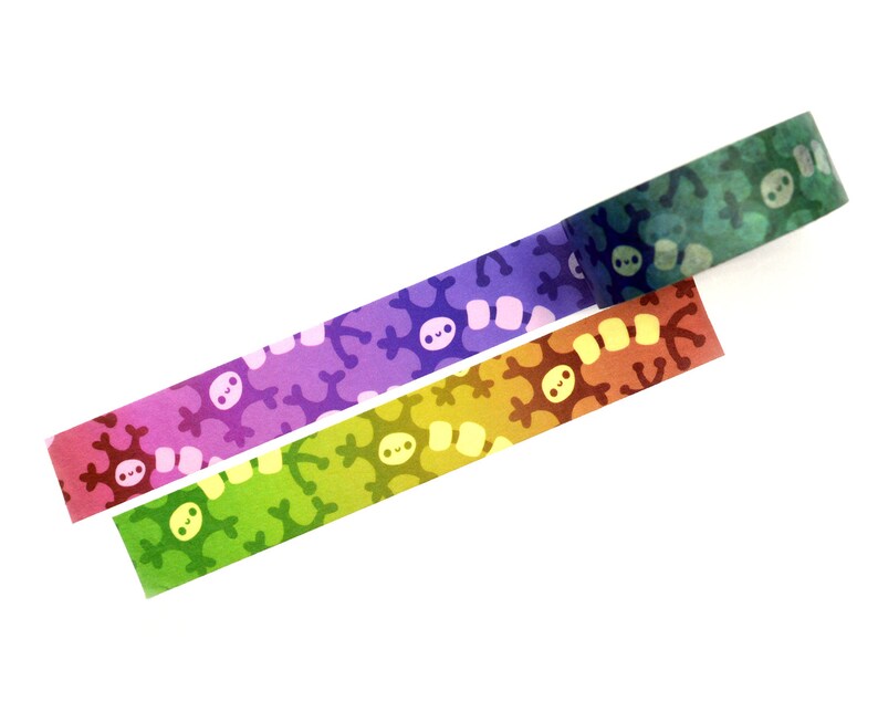 K&ouml;nnte beinhalten: Drei Rollen Washi-Tape mit einem Farbverlaufsmuster und einem sich wiederholenden Design eines Cartoon-Schneeflockens. Die Farben sind Lila, Gr&uuml;n und Orange.