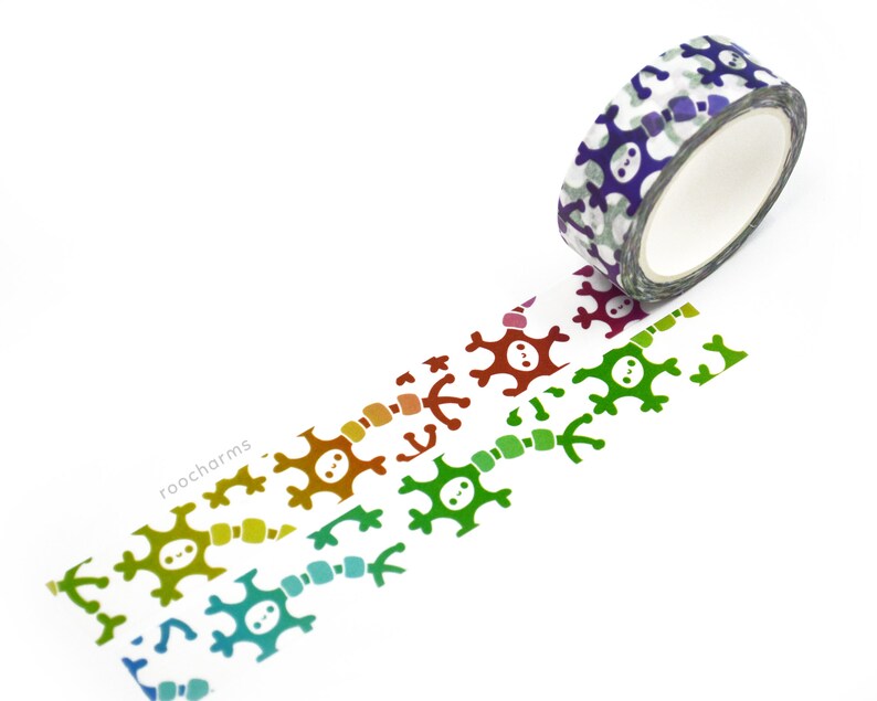 K&ouml;nnte beinhalten: Eine Rolle Washi-Tape mit einem sich wiederholenden Muster aus bunten Totenkopf- und Knochenkreuz-Designs. Das Band ist abgewickelt und zeigt das Muster in einem Regenbogen von Farben.