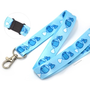 May include: A light blue lanyard with a repeating pattern of blue perfume bottles. The lanyard has a silver swivel clip and a black plastic adjustable buckle. The text "©roocharms" is printed on the lanyard.