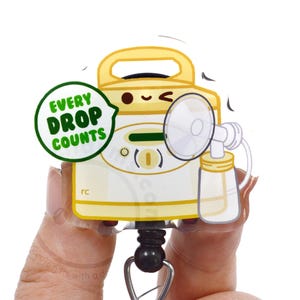 May include: A yellow breast pump badge reel featuring a cartoon face and a green speech bubble with the text EVERY DROP COUNTS. The device includes a clear collection bottle and a pump flange attached to the side, all mounted on a black retractable cord.