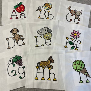 May include: Nine white fabric squares with embroidered letters of the alphabet, A through I, each with a corresponding image.  The images include an apple, a ball, a cat, a dog, an elephant, a flower, grapes, a horse, and an ice cream cone.