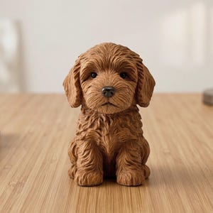 May include: A brown puppy figurine with detailed fur texture, sitting upright. The sculpture has a realistic appearance with a dark nose and expressive eyes. The figurine is a decorative item, likely for home decor.