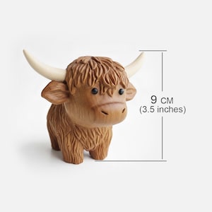 May include: A wooden Highland cow figurine, 3.5 inches tall, with detailed carving. The brown cow has a shaggy coat, small black eyes, and cream-colored horns. A charming decorative item.