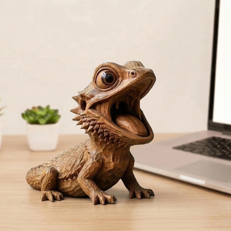 May include: A detailed wooden sculpture of a bearded dragon with its mouth open, tongue visible. The reptile is carved from light brown wood, showcasing intricate details. The sculpture is positioned on a wooden surface.