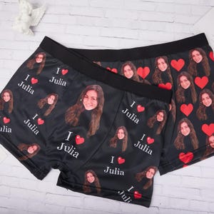 以下が含まれることがあります： 女性の顔、赤いハート、そして「I ❤️ Julia」のテキストが繰り返されるパターンが特徴の黒いボクサーパンツ。 ショーツは黒いウエストバンドがあり、滑らかな生地で作られています。 デザインは前面と背面に印刷されています。