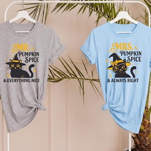May include: A grey t-shirt and a light blue t-shirt, both featuring a graphic of a black cat wearing a witch hat. The grey shirt has the text "MR. PUMPKIN SPICE & EVERYTHING NICE" and the light blue shirt has the text "MRS. PUMPKIN SPICE & ALWAYS RIGHT".
