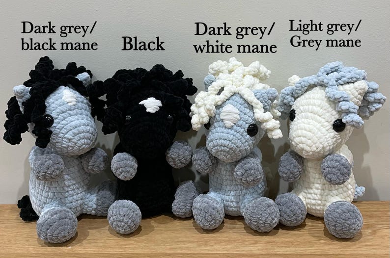 May include: Four handmade crochet horse plushies in various colors. The horses are light grey, black, and dark grey, with manes in black, white, and grey. The text "Dark grey/black mane", "Black", "Dark grey/white mane", and "Light grey/Grey mane" is visible.