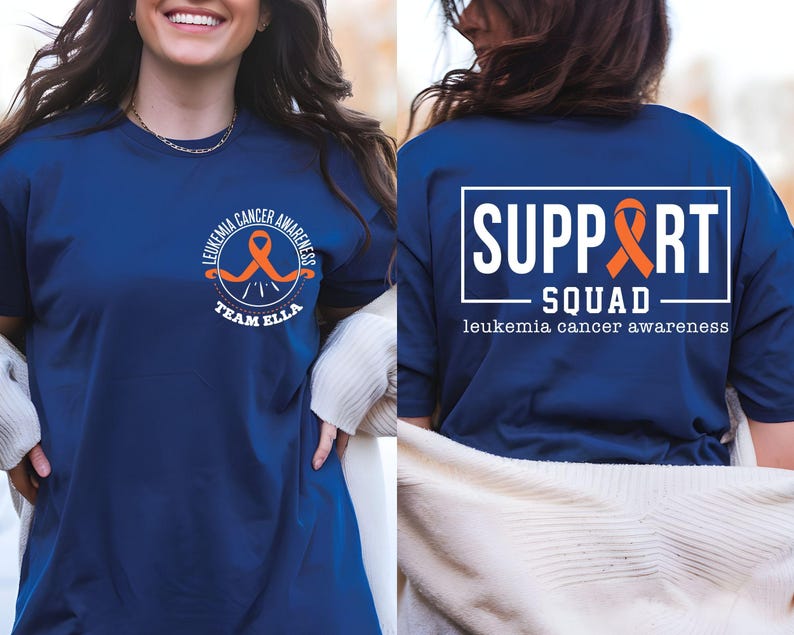 Puede incluir: Una camiseta azul marino con un gr&aacute;fico de cinta naranja circular en el pecho izquierdo con el texto LEUKEMIA CANCER AWARENESS TEAM ELLA. La parte posterior muestra un gran marco rectangular blanco con el texto SUPPORT SQUAD y una cinta.