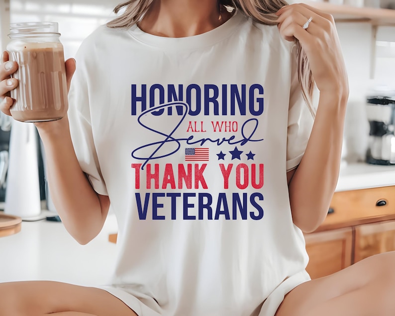 May include: White t-shirt with a blue and red graphic that says "Honoring All Who Served Thank You Veterans" with a small American flag and stars.