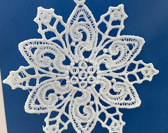 May include: White lace snowflake ornament with intricate details. The snowflake is hanging from a black string.