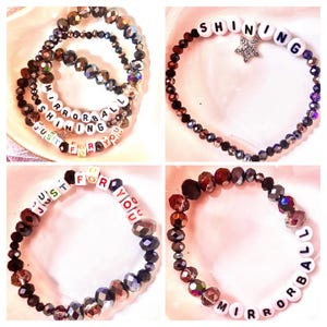 K&ouml;nnte beinhalten: Ein Set aus vier Perlenarmb&auml;ndern mit dunklen, facettierten, irisierenden Glasperlen und wei&szlig;en quadratischen Buchstabenperlen. Die Armb&auml;nder zeigen die Schriftz&uuml;ge "SHINING", "MIRRORBALL" und "JUST FOR YOU", eines enth&auml;lt einen sternf&ouml;rmigen Anh&auml;nger.