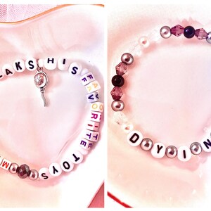 May include: Two beaded bracelets. The first bracelet is white with black lettering spelling "My Boy Only Breaks His Favourite Toys". The second bracelet is white with black lettering spelling "Do You Know G" and has purple and silver beads.